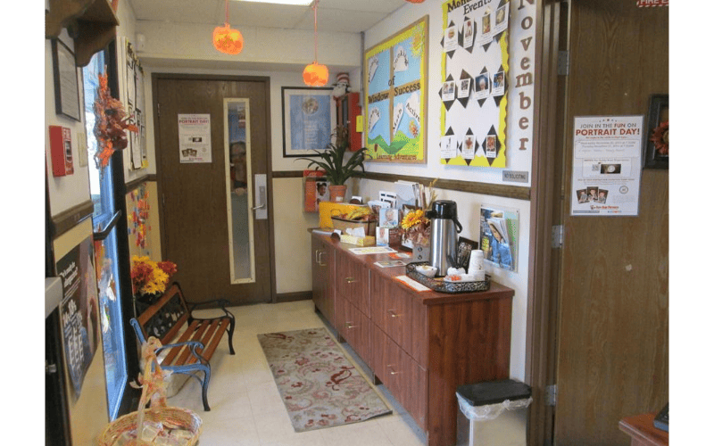 Hallway with a wooden cabinet, bulletin boards, and a bench