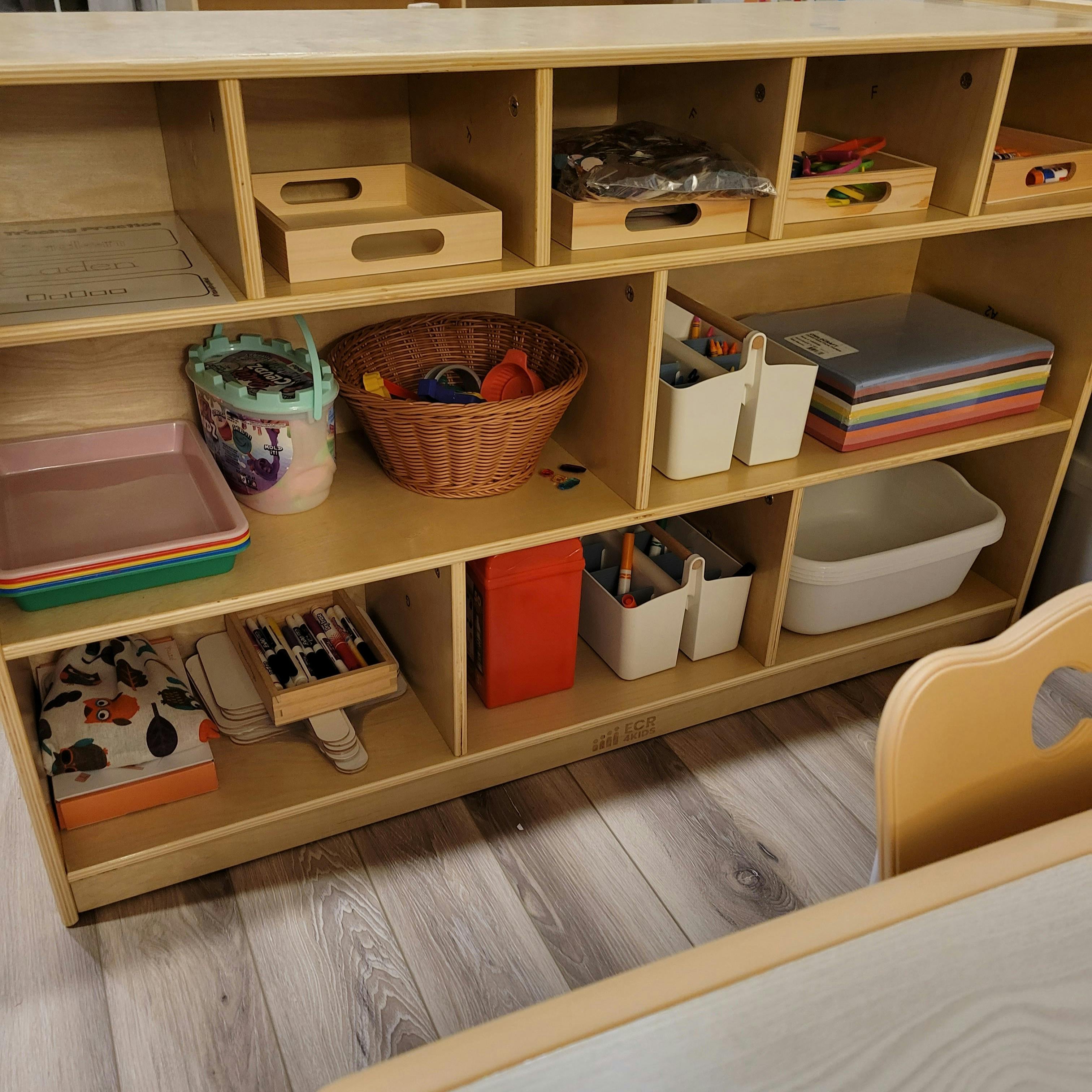 Wooden shelving unit with various items, including baskets, bins, and trays