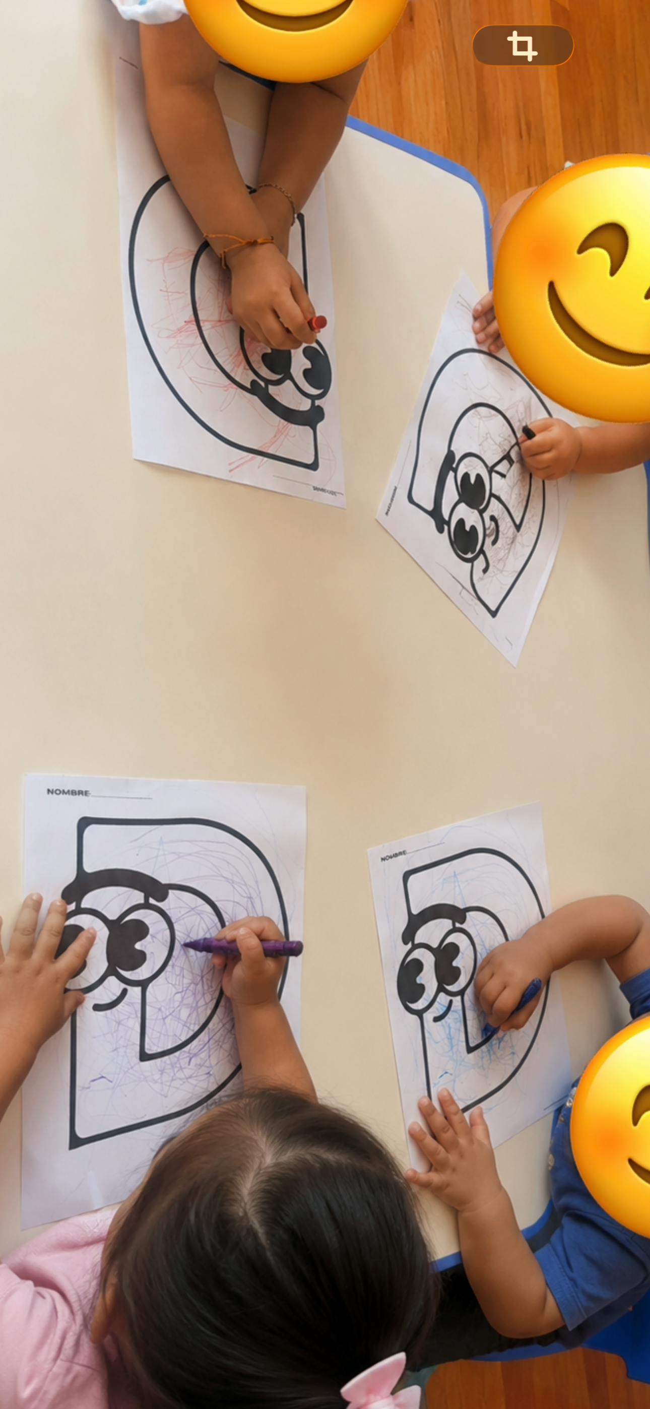 Children coloring letters on paper at a table