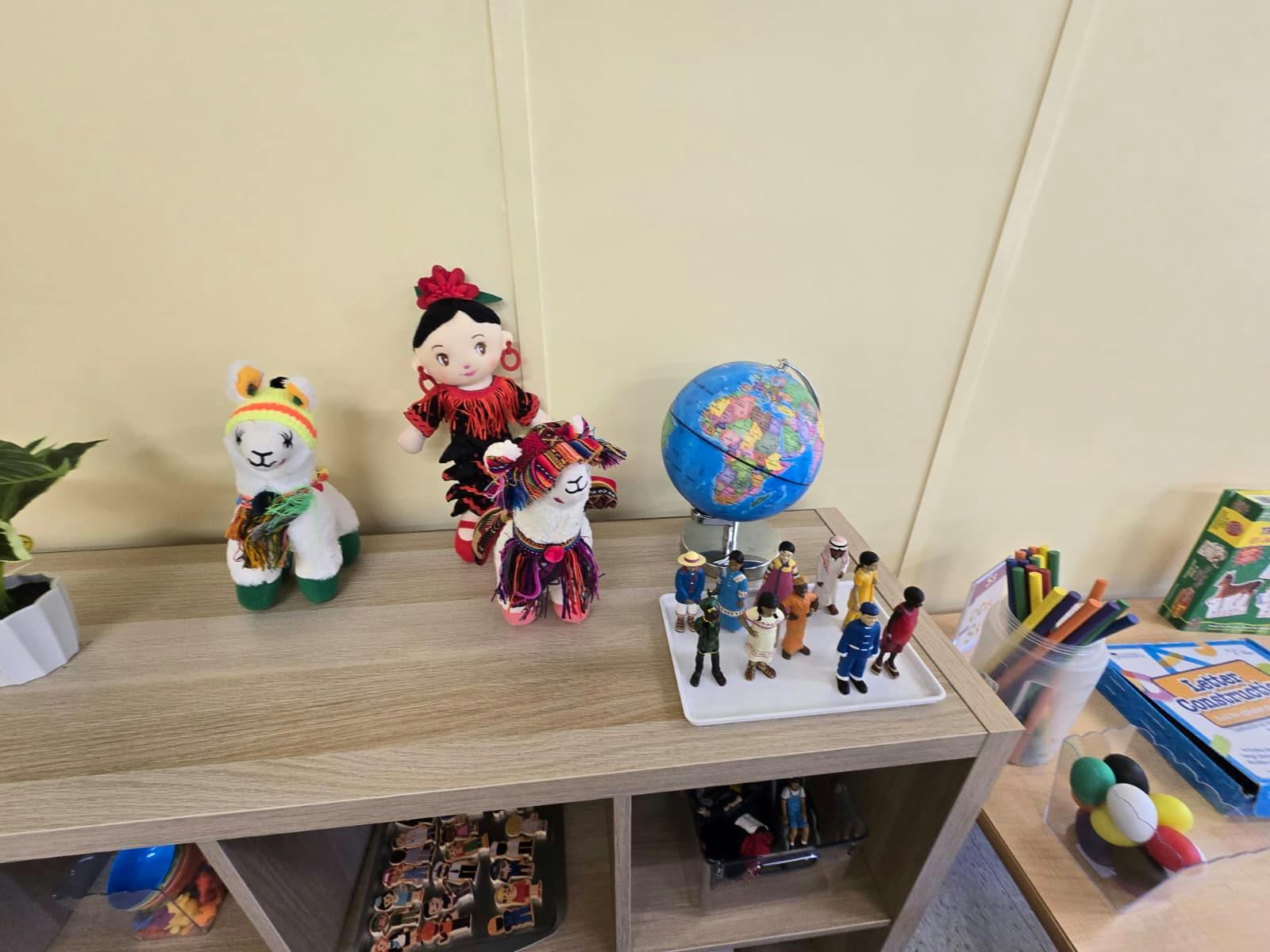 Plush toys, a globe, and miniature figures on a classroom shelf