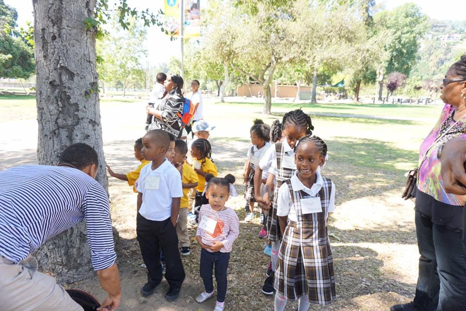 Adult and children gathered around a tree outdoors
