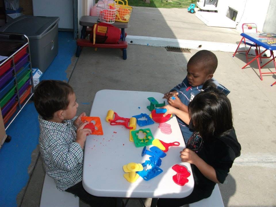 Three children playing with toys at a table