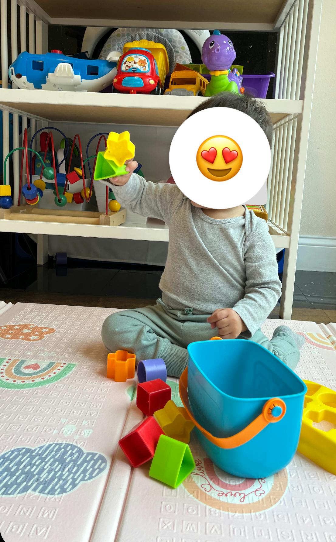 Child sitting on a playmat holding a yellow star toy