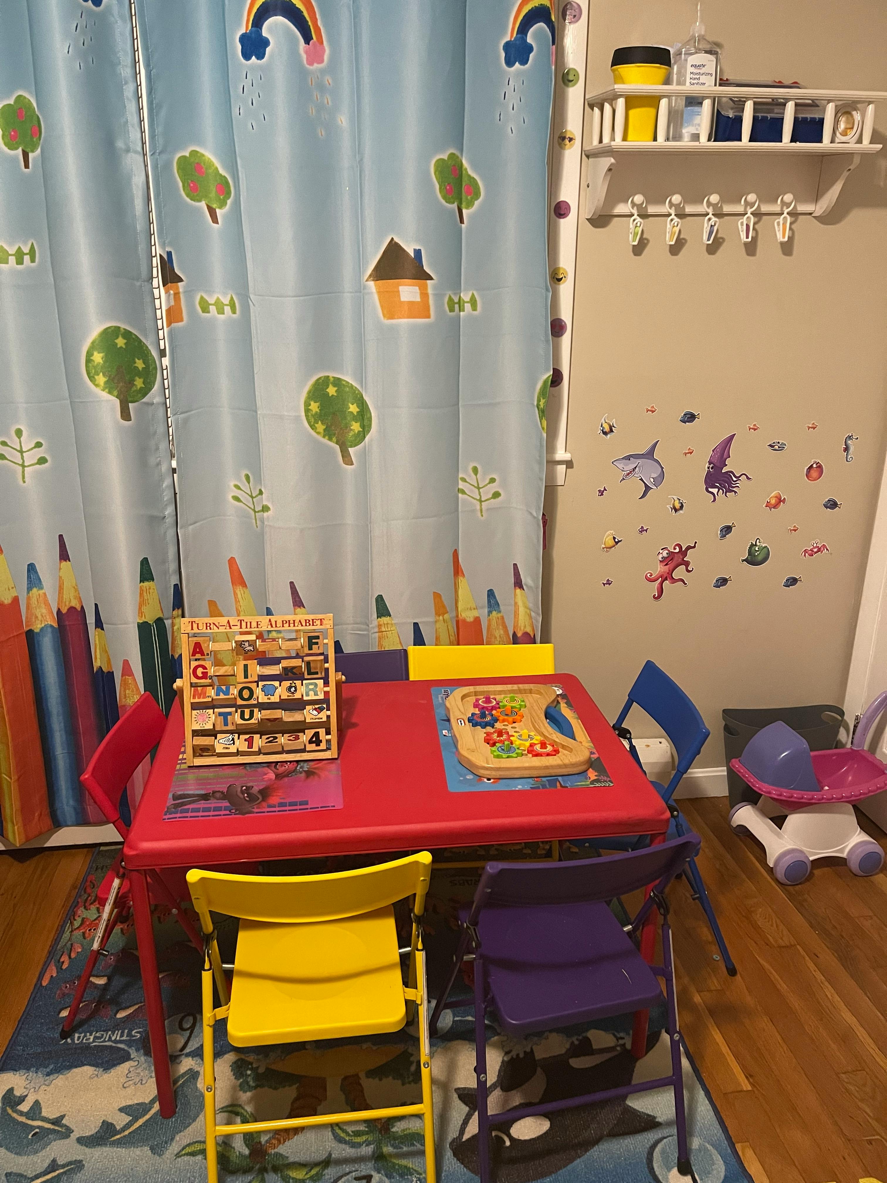 Children's play area with a red table and colorful chairs