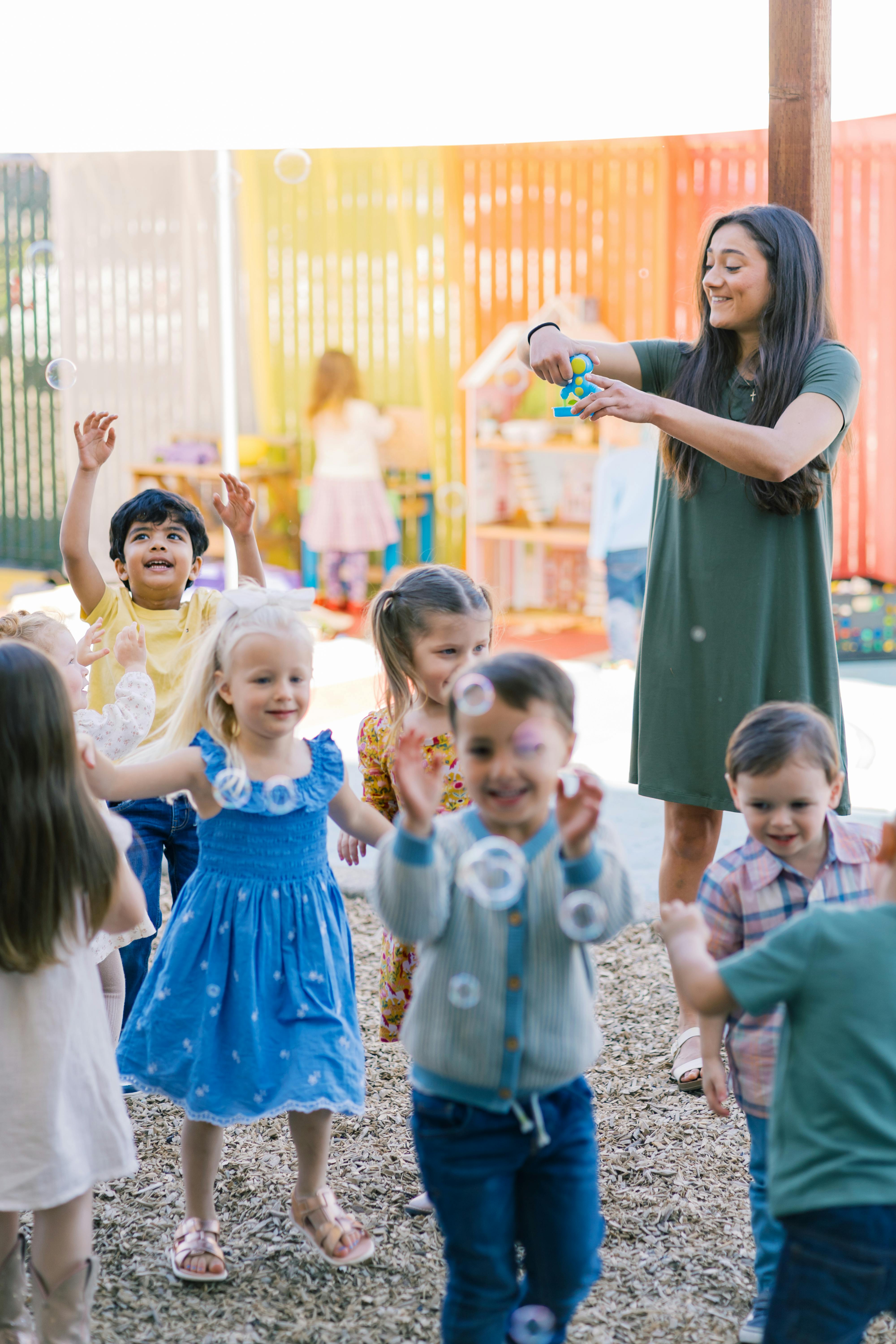Adult person blowing bubbles for a group of young children