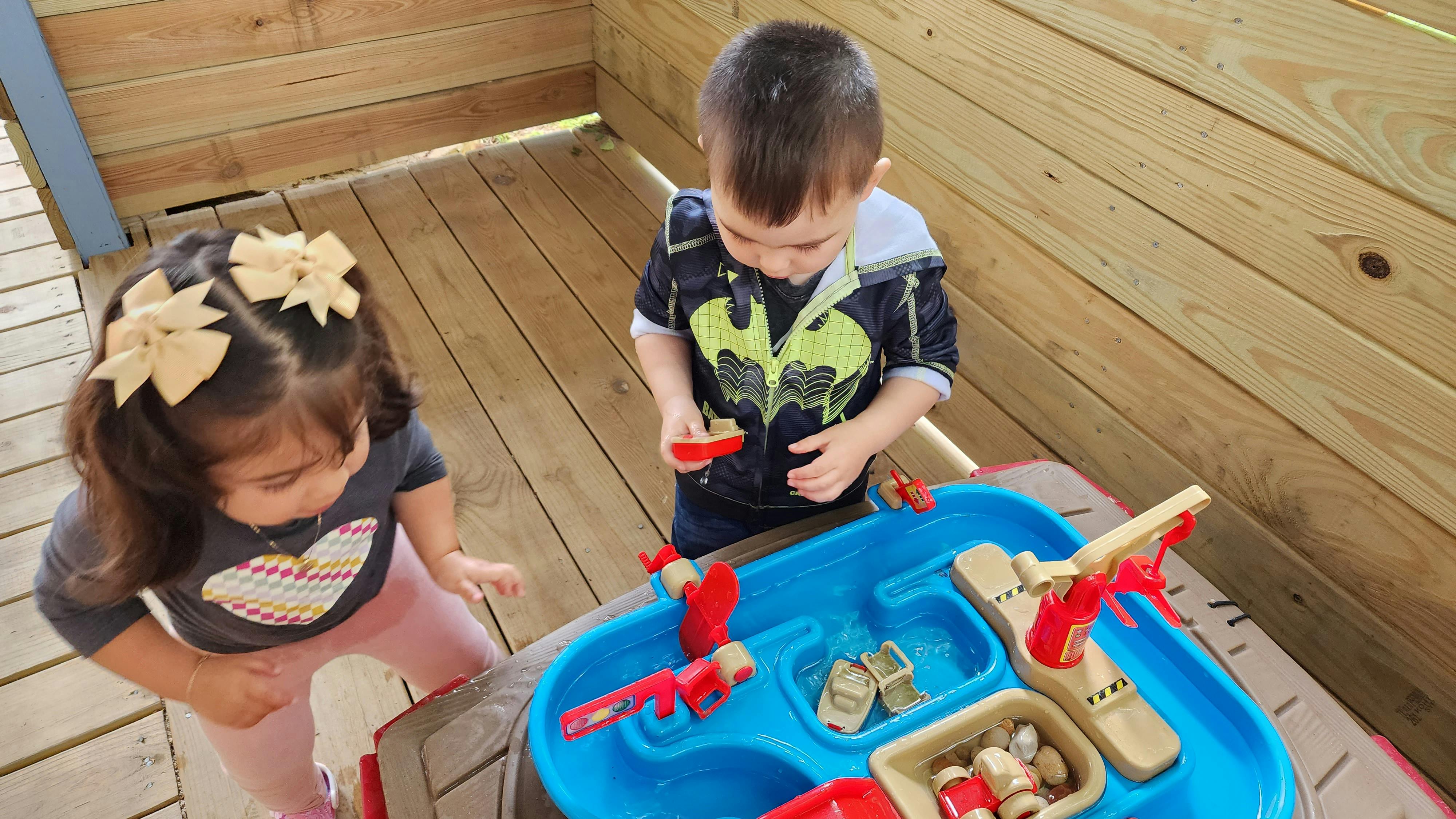 Two children playing with a water table