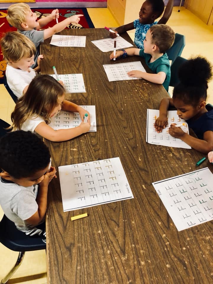 Children sitting at a table writing on worksheets