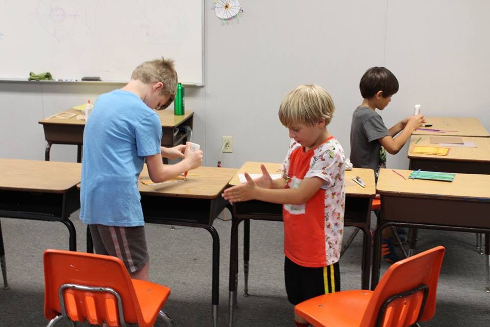 Three children working at desks in a classroom