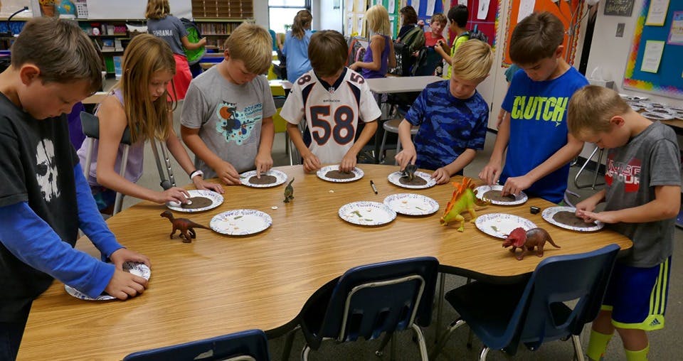 Children at a table with plates and dinosaur toys