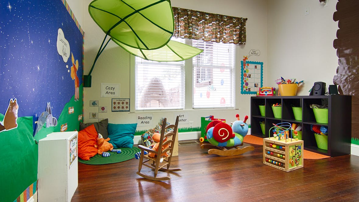 Playroom with colorful wall murals, rocking chair, and toys