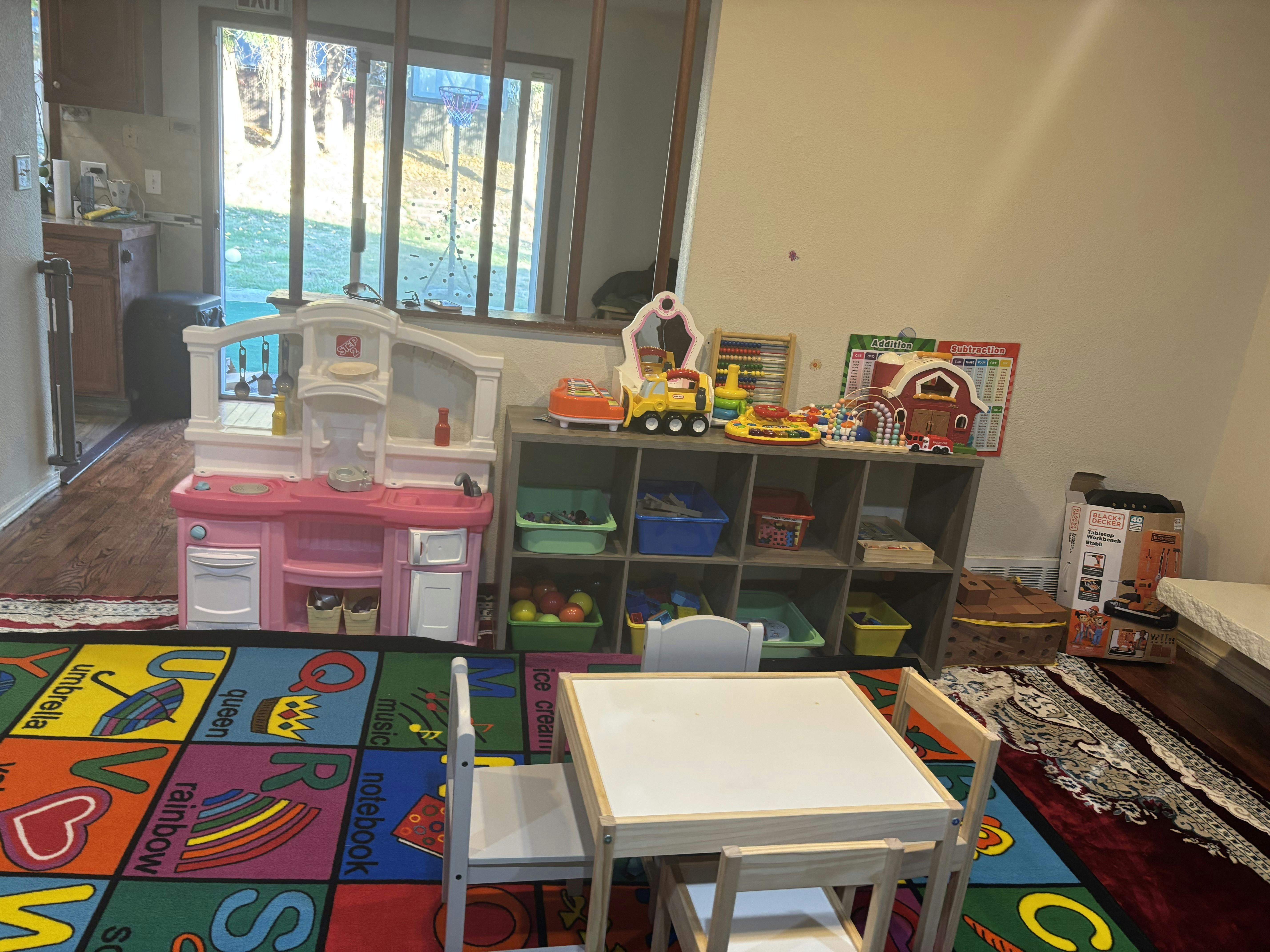 Playroom with a toy kitchen, storage shelves, and a small table with chairs