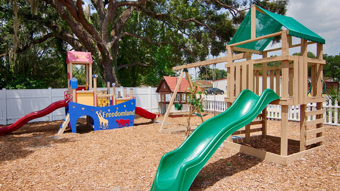 Playground with wooden play structure, green slide, and red slide