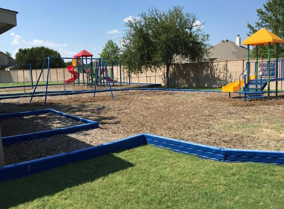 An empty playground with wood chips, swings, and two play structures with slides