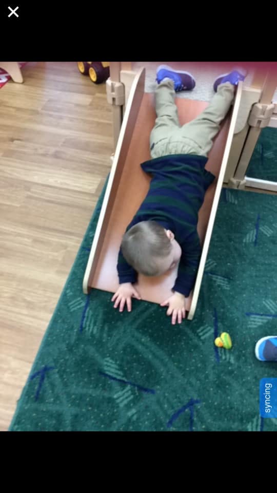 Child sliding headfirst down a small indoor slide
