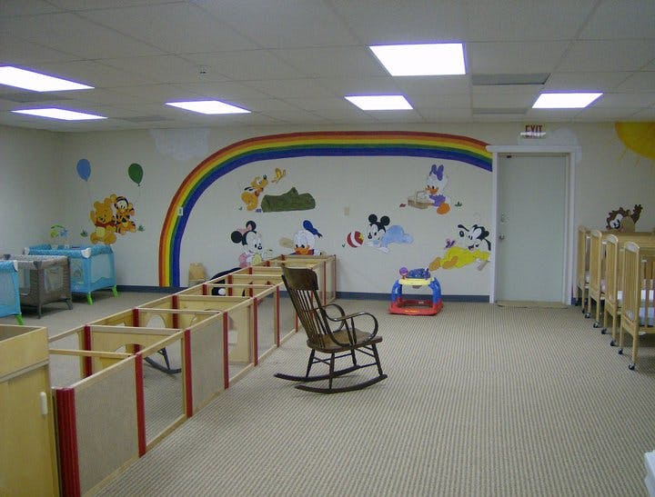 Nursery room with cribs, playpen, rocking chair, and wall murals