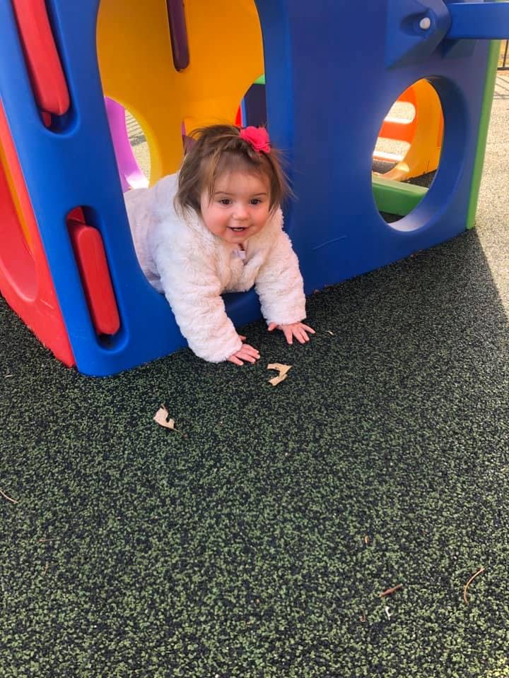 Child crawling out of a colorful play structure