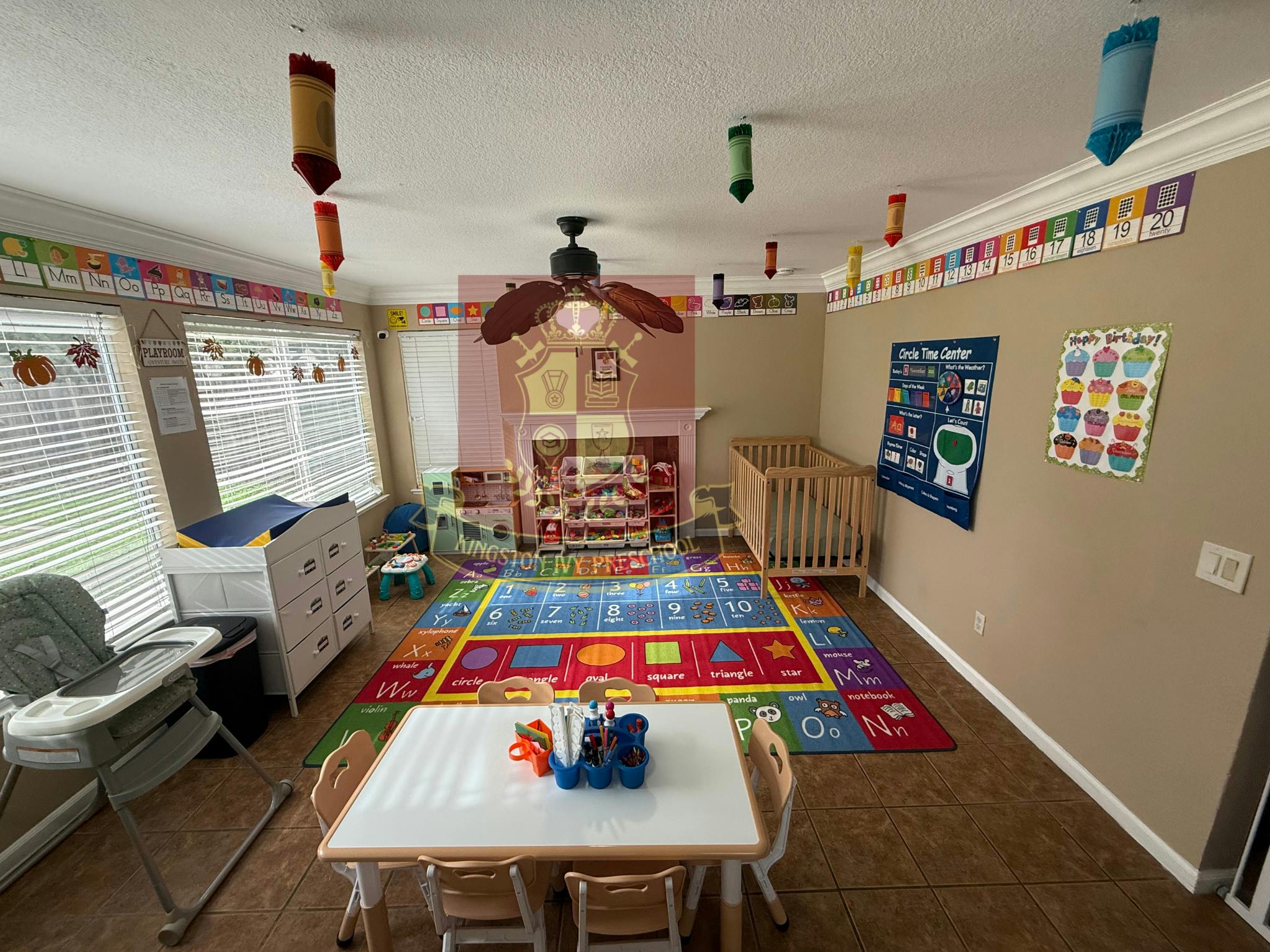 Childcare room with cribs, changing table, playmat, and small table with chairs