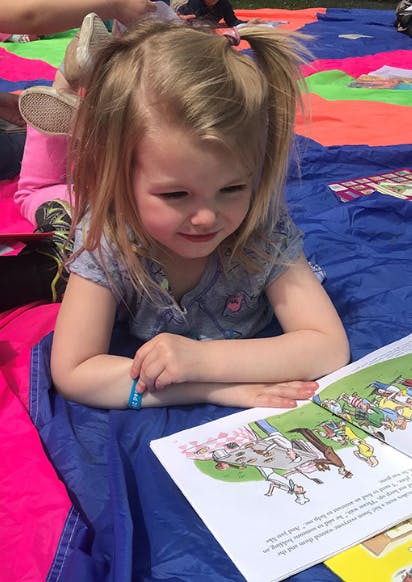 Child with pigtails looking at an open book
