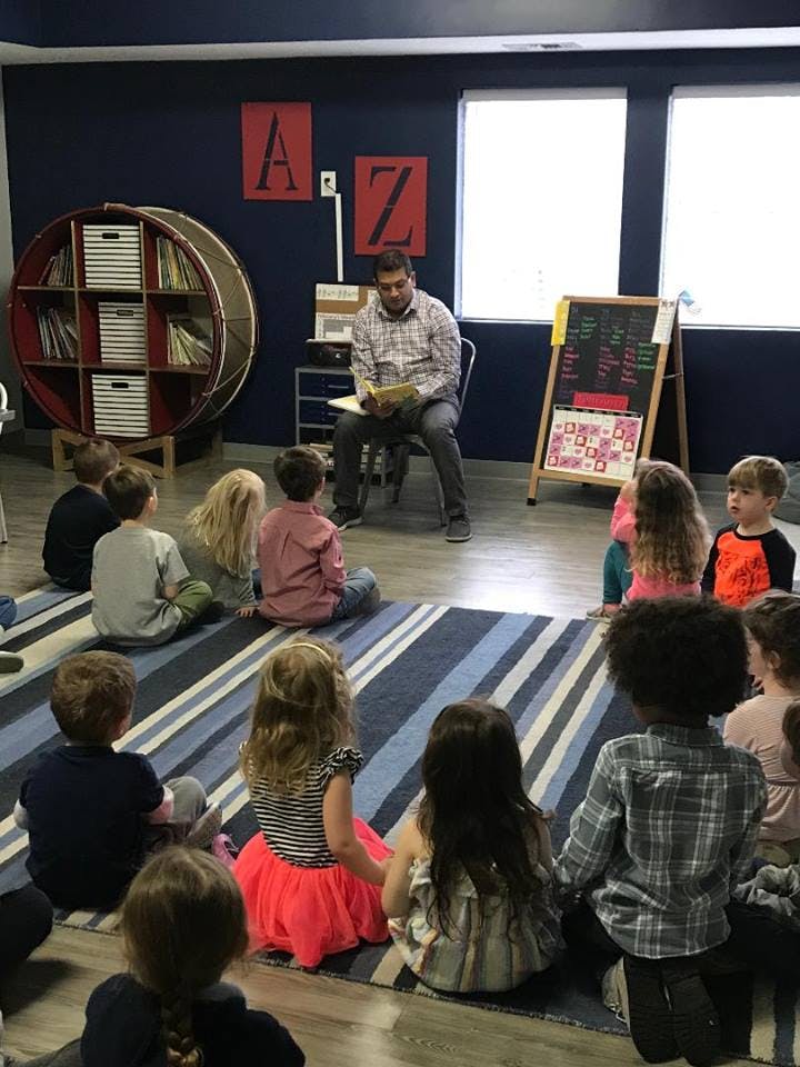 Person reading to children sitting on a rug