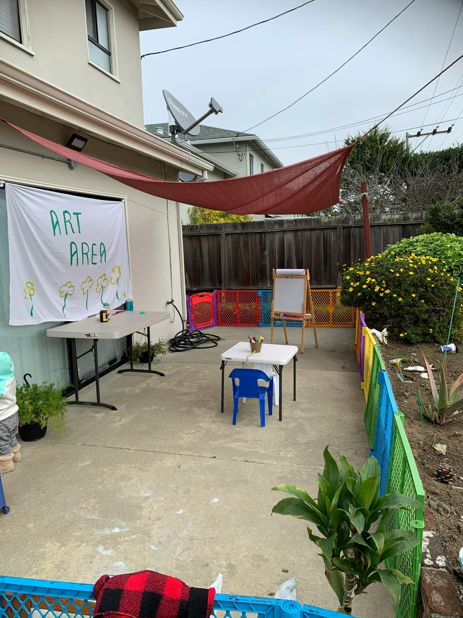 Outdoor art area with tables, chairs, an easel, and a banner that reads "ART AREA"