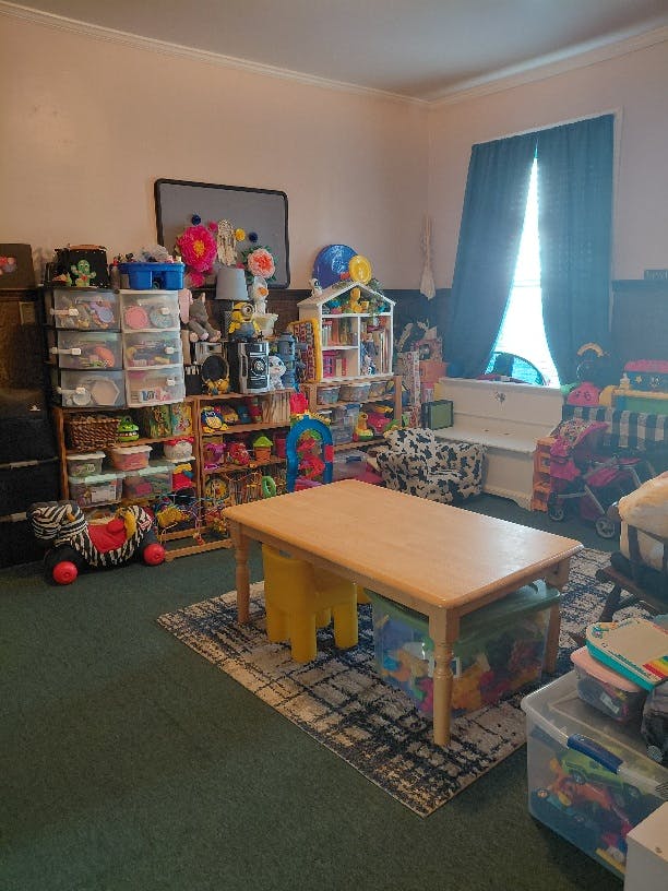 Playroom with a wooden table, chairs, and many toy storage bins