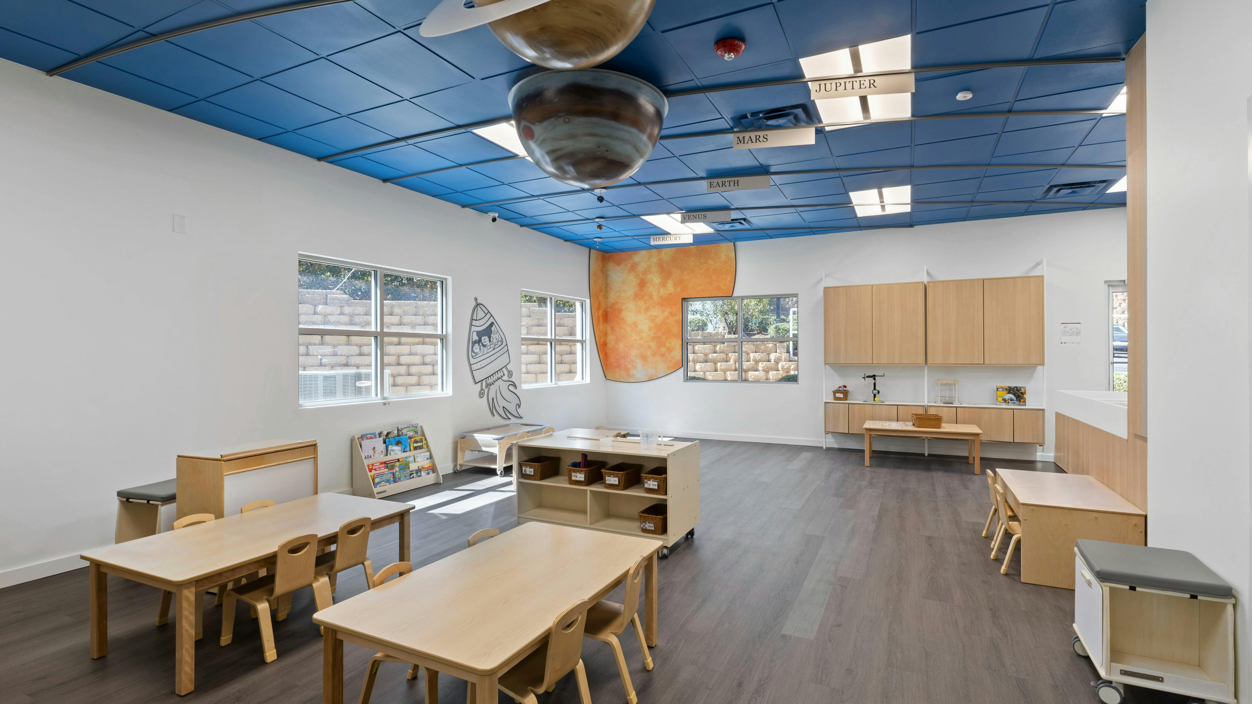 Classroom with planet models on the ceiling and child-sized tables and chairs