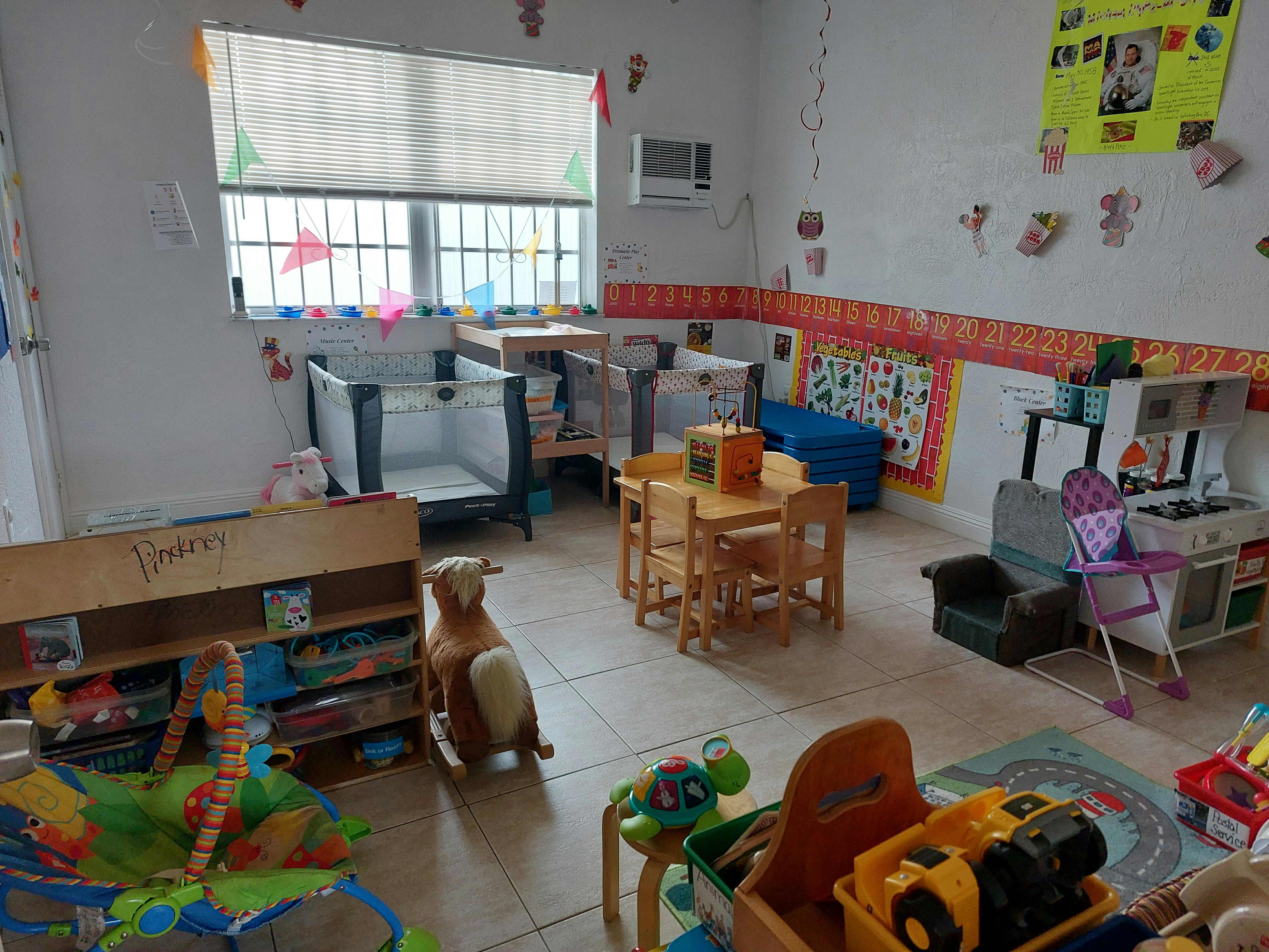 Daycare room with cribs, small tables, and toys