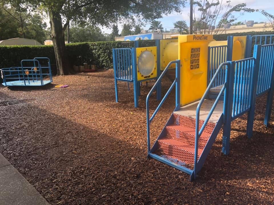 Playground with blue and yellow play structure and a merry-go-round