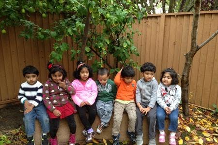 Six children sitting in a row outdoors