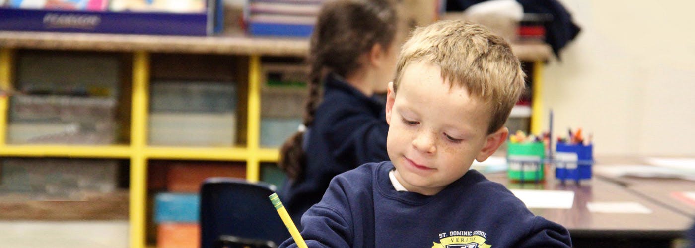 Child writing at a desk in a classroom