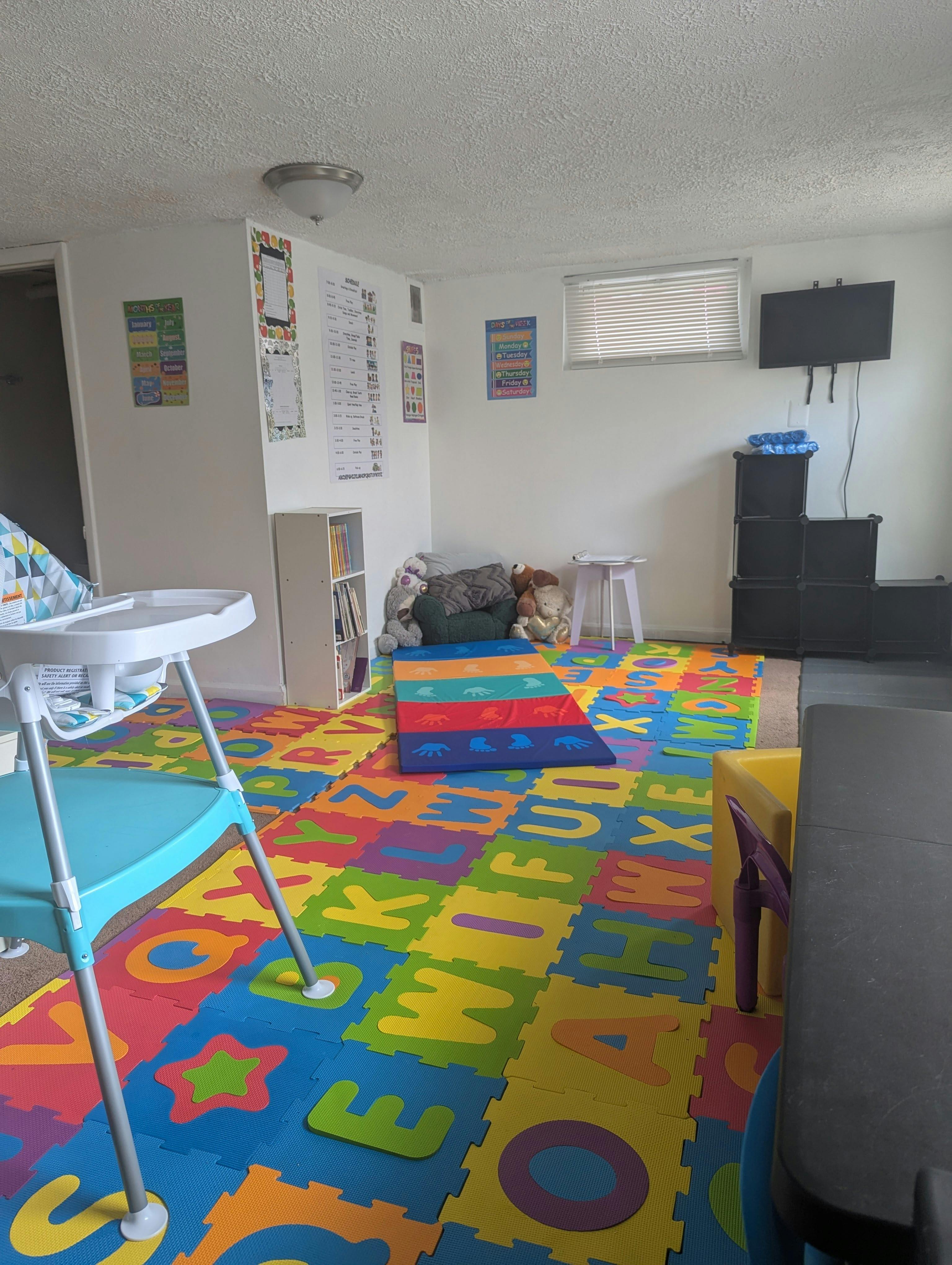Playroom with colorful alphabet floor mats, a high chair, and wall charts