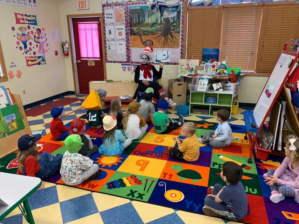 Person in Cat in the Hat costume reading to children in a classroom