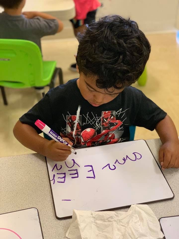 Child writing on a small whiteboard with a marker