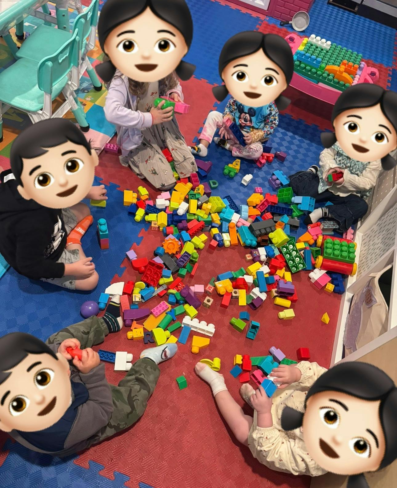 Children sitting on a play mat building with plastic construction blocks