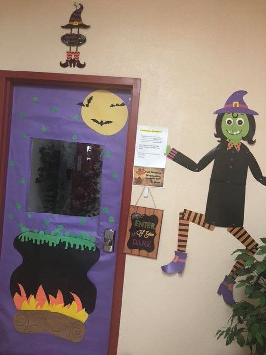 Door decorated with Halloween cutouts of a witch, moon, bats, and cauldron