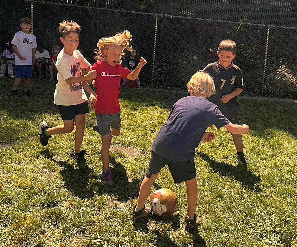 Children playing soccer on a grassy field