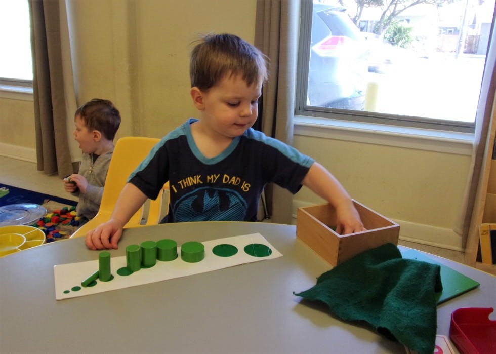 Child playing with green shapes on a table
