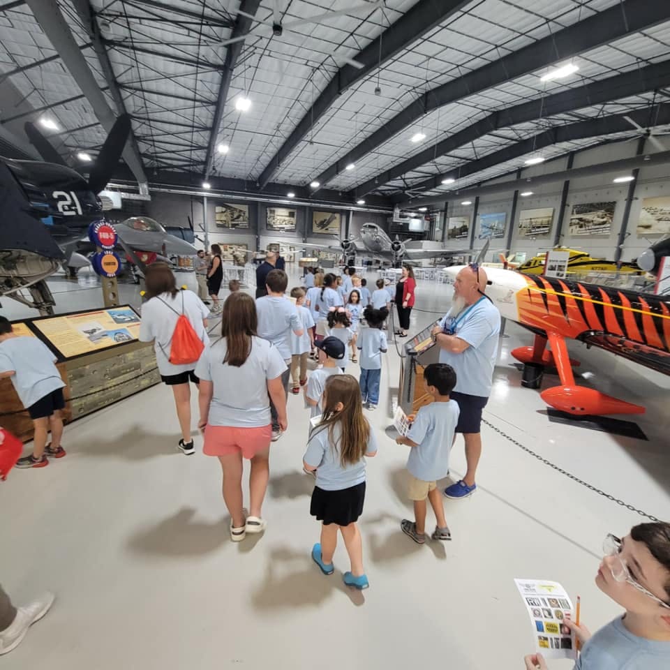 Group of people and children on a tour in an aircraft museum