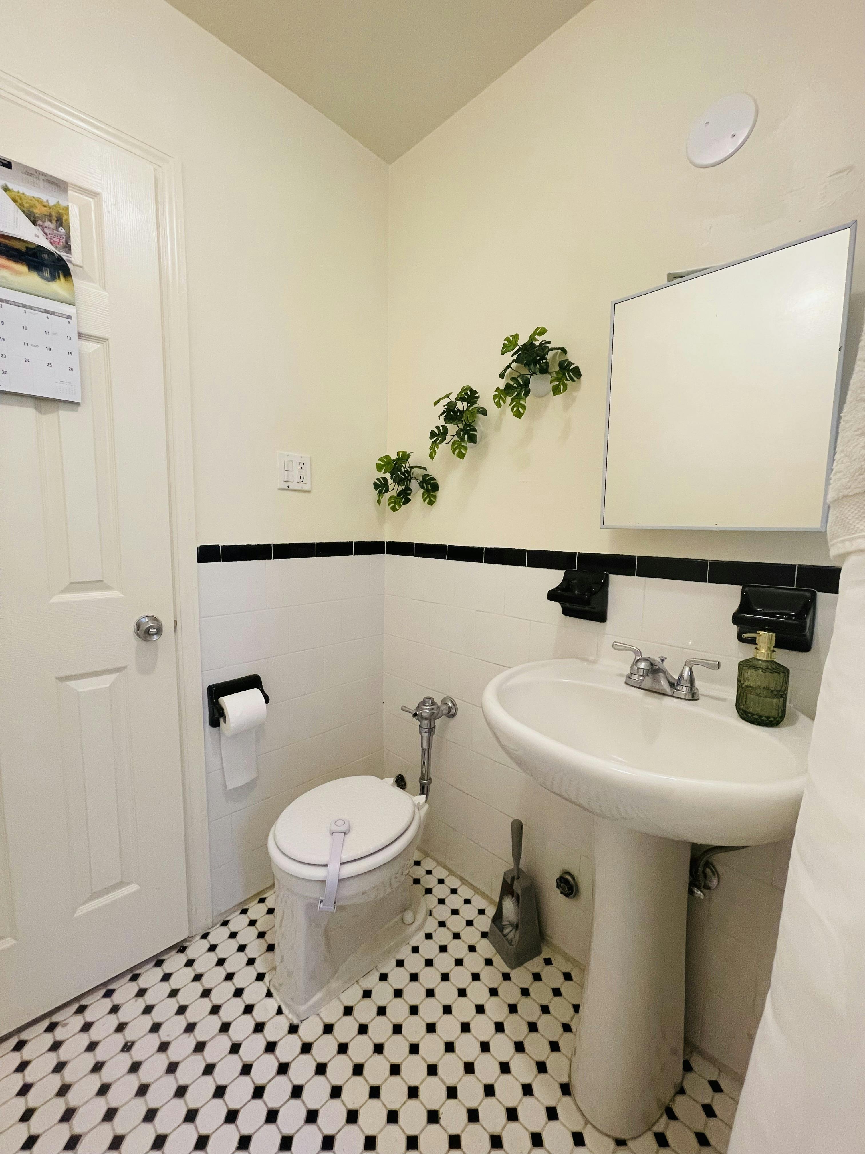 Bathroom with toilet, pedestal sink, and black and white tiled floor