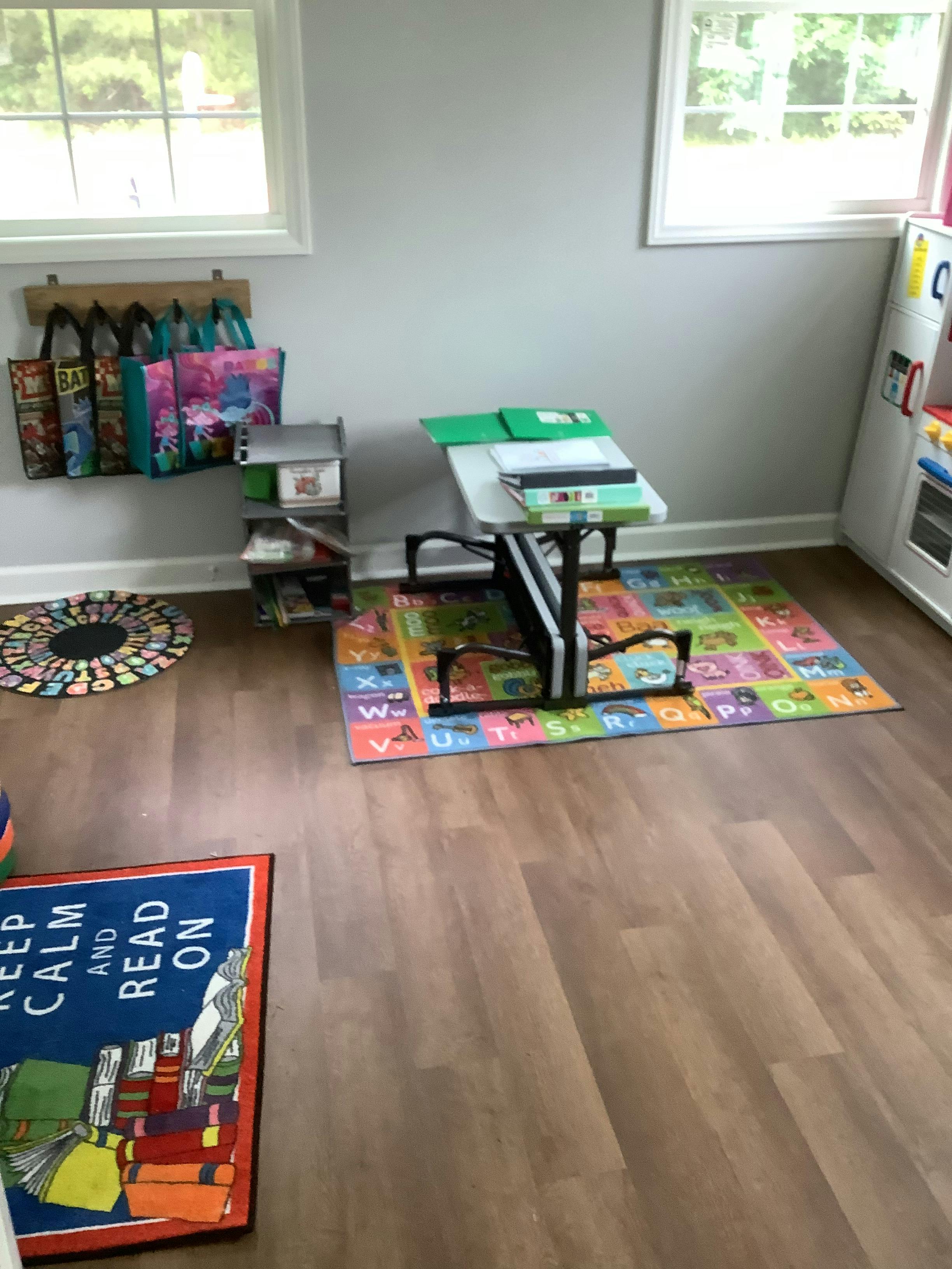 A child's desk and chair on an alphabet rug in a room with wood floors