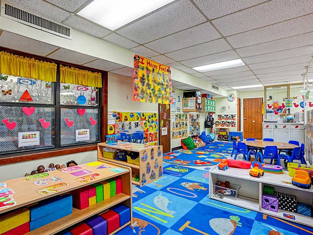 Colorful classroom with toys, tables, chairs, and windows with heart decorations