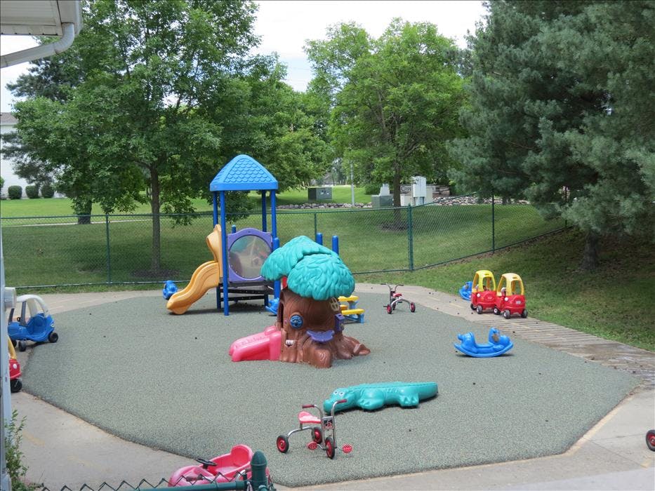 A children's playground with a slide, play structure, and ride-on toys