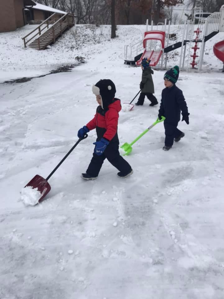 Children shoveling snow on a snowy playground