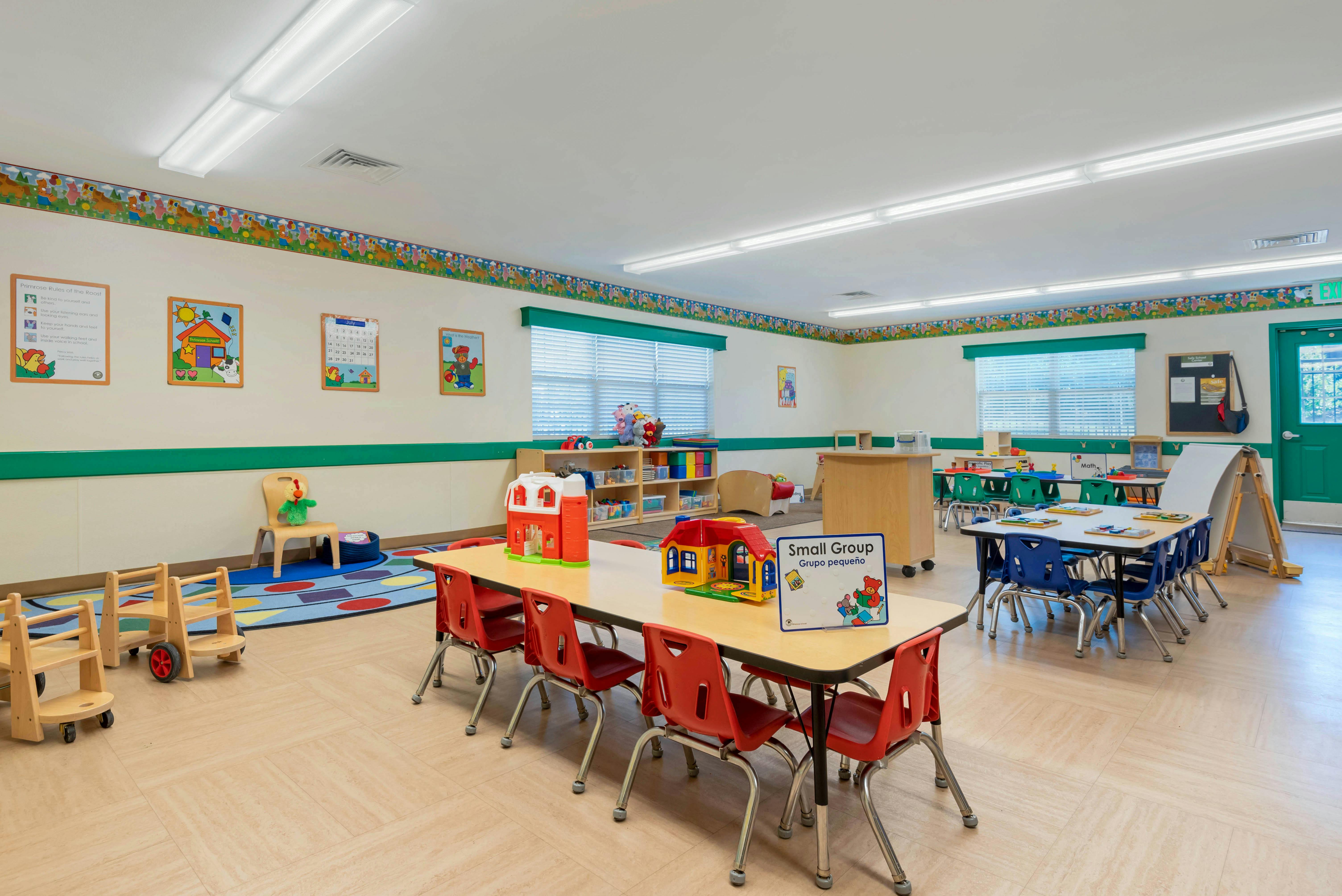 A colorful empty classroom with tables, chairs, and learning decorations