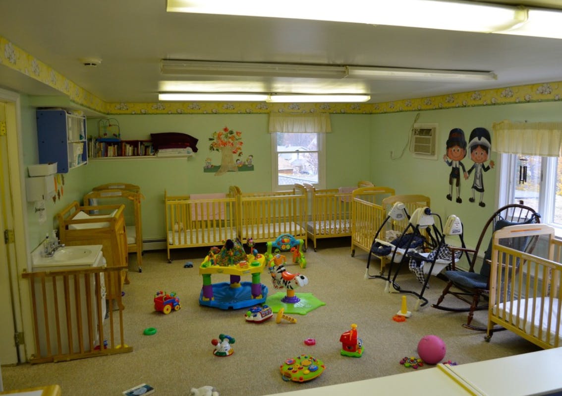 Nursery room with multiple cribs, baby swings, and toys on the floor