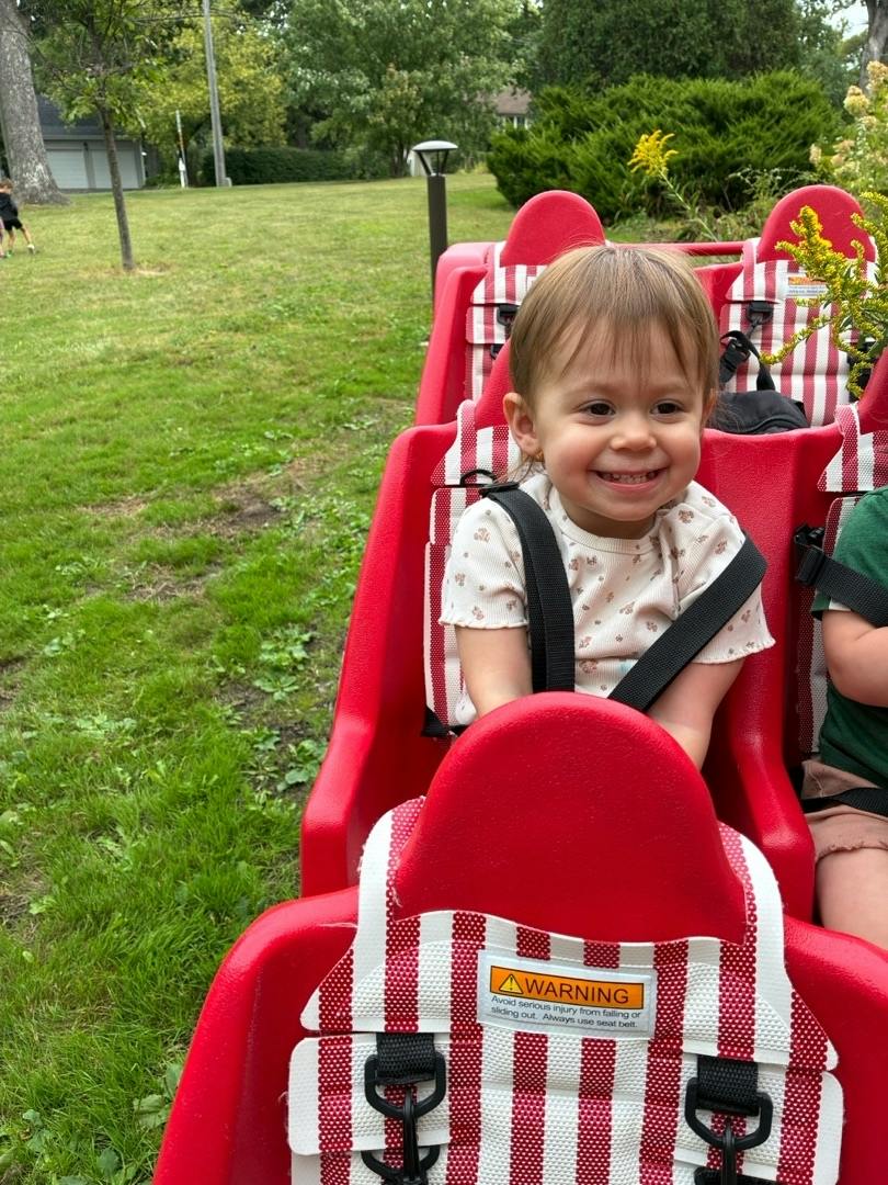 Child sitting in a red ride seat outdoors