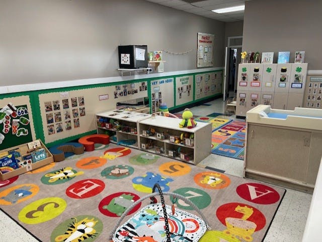 Childcare classroom with colorful rugs, cubbies, and bulletin boards