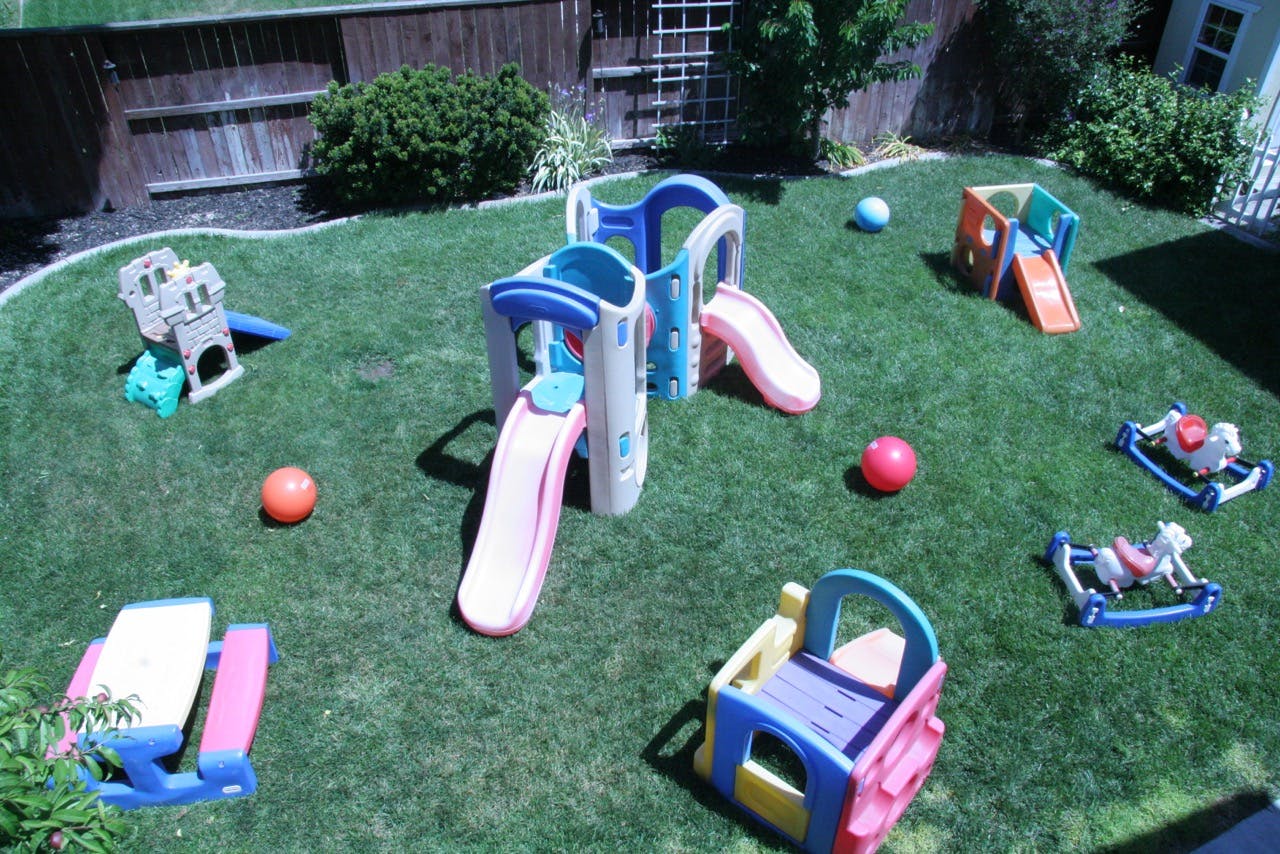 Playground with slides, rocking horses, and balls on grass