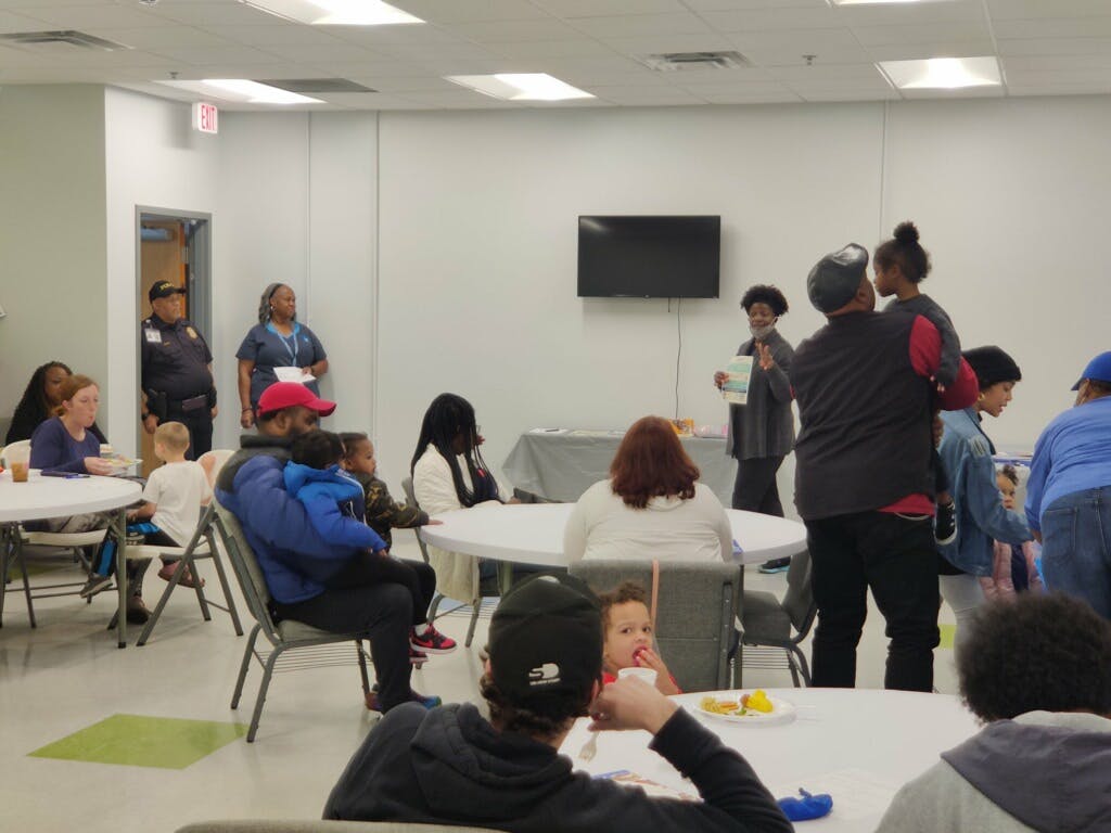 People gathered in a room with tables, some sitting and some standing