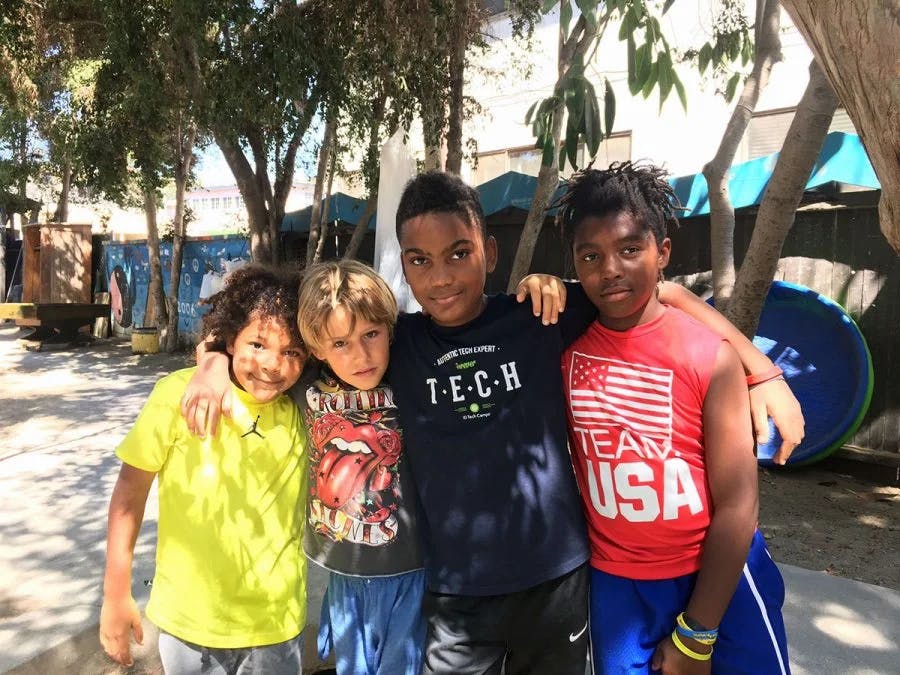 Four children standing side by side with arms around each other
